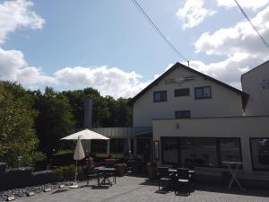 ein Gebäude mit einer Terrasse mit Tischen und einem Sonnenschirm in der Unterkunft Hotel Waldterrasse in Rengsdorf
