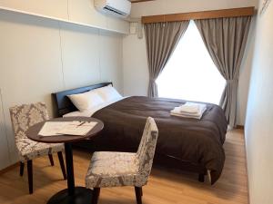 1 dormitorio con 1 cama, mesa y sillas en Y' RISE TO HOTEL Miyakojima, en Isla Miyako