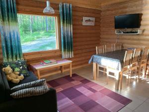 ein Wohnzimmer mit einem Tisch und einem TV in einer Hütte in der Unterkunft Lappalaisen lomamökit Mäntypirtti in Puumala