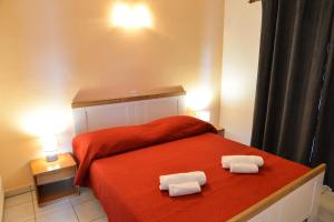 a bedroom with a red bed with two towels on it at Apartments Lonić in Kukljica