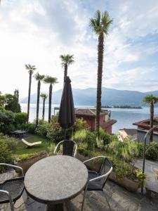 a patio with a table and chairs and palm trees at Casa Eva in Ronco s/Ascona - Porto Ronco