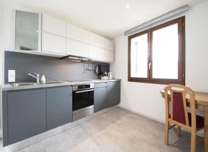 una cucina con armadi grigi, un lavandino e una finestra di Casa Eva a Ronco sopra Ascona