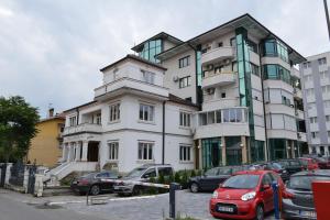 Un gran edificio blanco con coches aparcados delante. en Lasofti Vrnjacka Banja, en Vrnjačka Banja