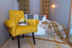 a bedroom with a yellow chair and a bed at TOPILCHE APARTMENT in Ternopil