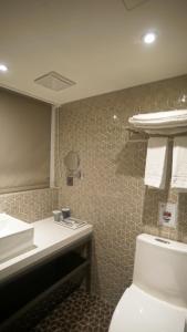 a bathroom with a toilet and a sink and a mirror at City Suites - Taoyuan Station in Taoyuan