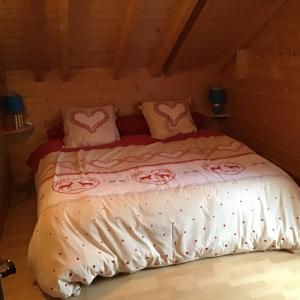 Chalet le Grizzly في لو ثولي: غرفة نوم بسرير وبطانيات ووسائد وردية وبيضاء