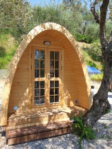 un pequeño cobertizo de madera con una gran ventana frente a un árbol en Campeggio Gianna Golfo dei Poeti, en Lerici