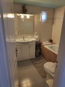 a bathroom with a sink and a tub and a toilet at Harbour View House in Mithymna