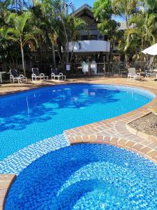 a large swimming pool with blue water and chairs at Bay of Palms in Gold Coast