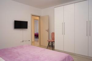 1 dormitorio con armarios blancos y TV en la pared en Apartman TESSA, en Vela Luka