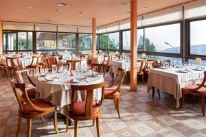 un restaurante con mesas, sillas y ventanas en Can Fisa Hotel & Apartments en Corbera de Llobregat