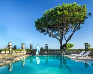 ein Schwimmbad mit einem Baum im Hintergrund in der Unterkunft Luxury Relais Villa Magdalena in Ischia