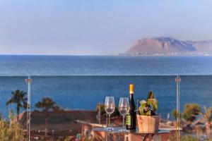 Lilium Luxury Suites في أييا مارينا نيا كيذونياس: طاولة مع زجاجات النبيذ والاكواب على الشاطئ