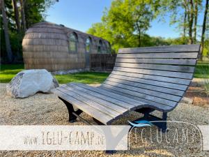 a wooden bench sitting in front of a building at Iglu Camp Heidewald in Sassenberg