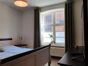 ein Schlafzimmer mit einem Bett und einem großen Fenster in der Unterkunft Nikolaikirch-Hof in Wismar