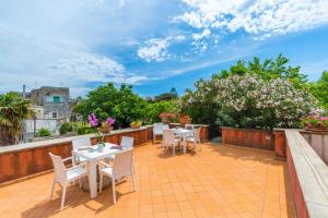 Un patio con mesas y sillas en un balcón. en La TERRAZZA sul GIARDINO, en Procida