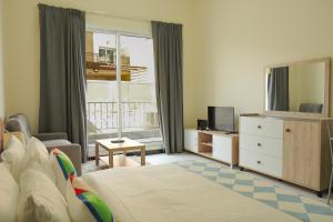 a bedroom with a bed and a tv and a couch at SHH - Furnished Studio in Knight Bridge Court A, JVC in Dubai