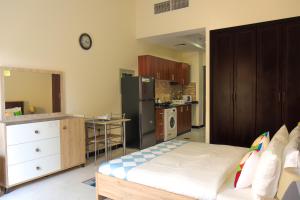 a room with a kitchen with a bed and a refrigerator at SHH - Furnished Studio in Knight Bridge Court A, JVC in Dubai