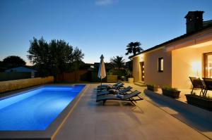 een zwembad met ligstoelen naast een huis bij Villa Lavanda in Galižana