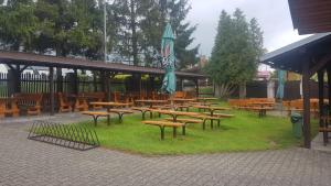 a group of wooden tables and benches with an umbrella at Hotel U Jelena in Havířov