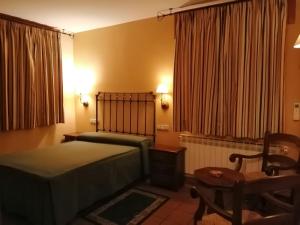 um quarto com uma cama, uma mesa e uma cadeira em Hotel Rural & SPA Puente del Duratón em Sepúlveda