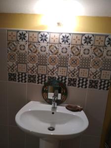 a bathroom with a sink and tiles on the wall at Daphrose chambre in Lachau