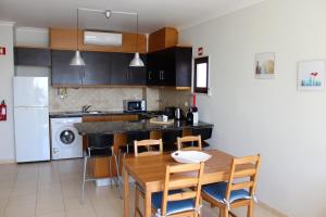 a kitchen with a wooden table and chairs in it at Sunny Vilamoura Pool Apartment- Free Parking- Fiber Wi-Fi in Vilamoura