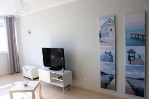 a living room with a flat screen tv on a wall at Sunny Vilamoura Pool Apartment- Free Parking- Fiber Wi-Fi in Vilamoura