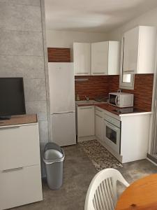 una pequeña cocina con armarios blancos y una mesa en Appartement à Marseillan plage accès direct à la plage, en Marseillan