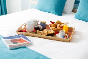 a tray of breakfast foods and drinks on a bed at Best Western Hôtel Royan Océan in Royan