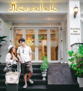 a man and woman walking down the stairs outside of a restaurant at Noursabah Boutique Bed Bangkok in Bangkok