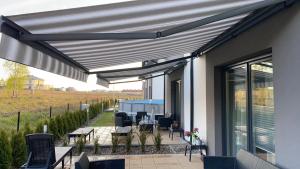 awning over a patio with chairs and tables on a house at Aqua Your Stay Apartamenty - Domy BartArt in Mielno