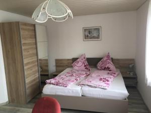 Un dormitorio con una cama con almohadas rosas. en Ferienwohnungen Müller, en Bad Staffelstein
