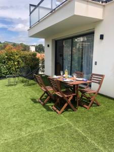 une table et des chaises en bois sur une pelouse dans l'établissement Appartement Centre ville Cassis, à Cassis