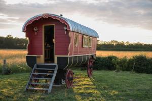 ein kleiner roter Zugwagen auf einem Feld in der Unterkunft La Roulotte des Grillots in Beaulon