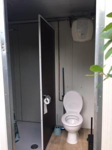 - une salle de bains avec des toilettes blanches dans une cabine dans l'établissement Tiny House de Wood Lodge, à Ootmarsum