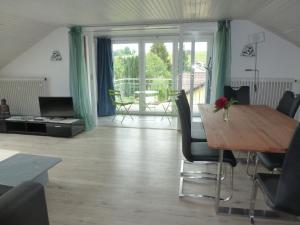 ein Wohnzimmer mit einem Tisch und Stühlen sowie einem Balkon in der Unterkunft Ferienwohnung Pickenhan in Scheidegg