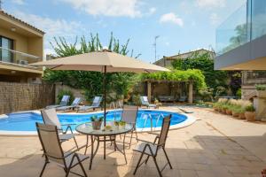 patio ze stołem, krzesłami i parasolem w obiekcie Casa Deluxe Alt Empordà Costa Brava - Private swimming pool w mieście Vilabertrán