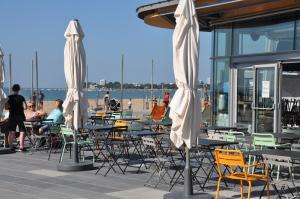 eine Außenterrasse mit Tischen, Stühlen und Sonnenschirmen in der Unterkunft Appartement cosy refait à neuf au coeur de Saint Nazaire à 300m du front de mer in Saint-Nazaire