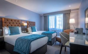 ダブリンにあるグランド キャナル ホテルのベッド2台とデスクが備わるホテルルームです。
