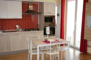 a kitchen with a white table and chairs and red tiles at Le Margherite in Cardano al Campo