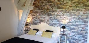 a bedroom with a brick wall and a bed at Auberge de Cartassac in Sarrazac