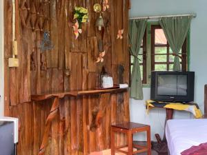 Habitación con pared de madera y TV. en Sam's House Kanchanaburi, en Kanchanaburi