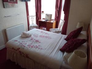 Un dormitorio con una cama grande con flores rojas. en Fjaerland Hotel, en Great Yarmouth