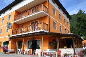 um edifício laranja com mesas e cadeiras em frente em Hotel Passo Buole em Vallarsa