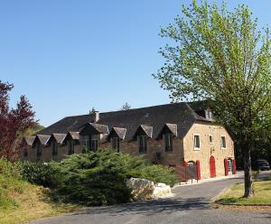 un grand bâtiment en briques avec un toit noir dans l'établissement Auberge de Cartassac, à Sarrazac