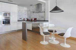 a white kitchen with a table and chairs at ATeRIAN GAZTETAPE I in Getaria