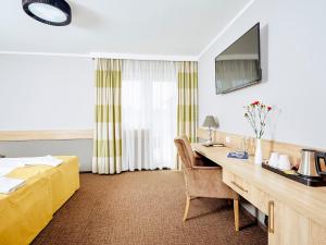ein Hotelzimmer mit einem Schreibtisch und einem Bett in der Unterkunft Hotel Mużakowski in Łęknica