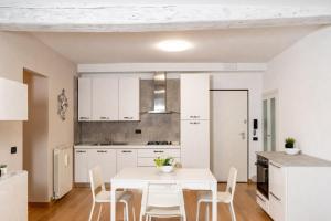 biała kuchnia z białym stołem i krzesłami w obiekcie Feel at Home - NEL CUORE DI LOVERE w mieście Lovere