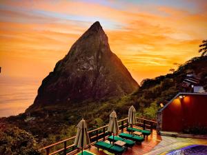 a mountain with a group of lounge chairs and umbrellas at Ladera Resort in Soufrière